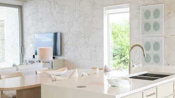 Een moderne keuken met een groot eiland, een ingebouwde televisie en uitzicht op groen.