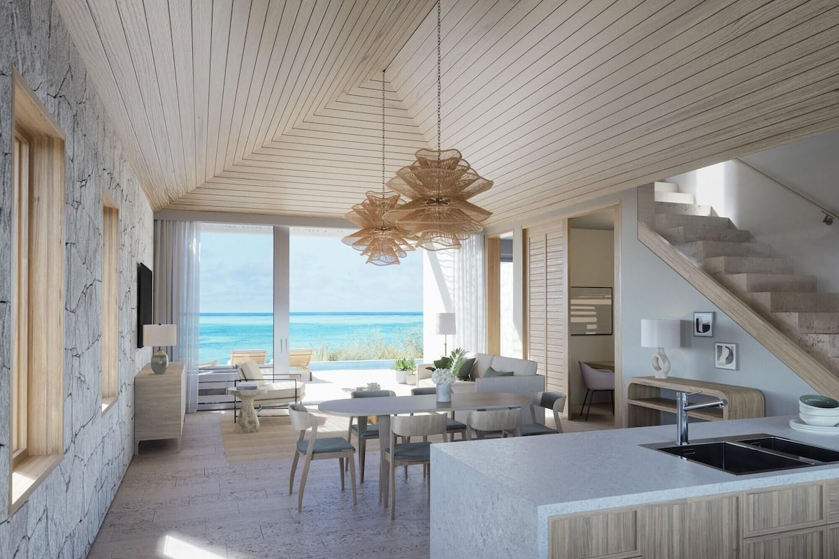 Un interior moderno con isla de cocina, comedor y vista al océano.
