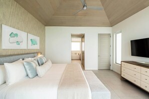 A bedroom with a bed, a TV, a ceiling fan, and artwork on the wall. - Rock House (Providenciales)