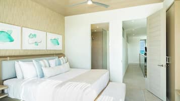 A modern bedroom with a large bed, a ceiling fan, and a view of the balcony.