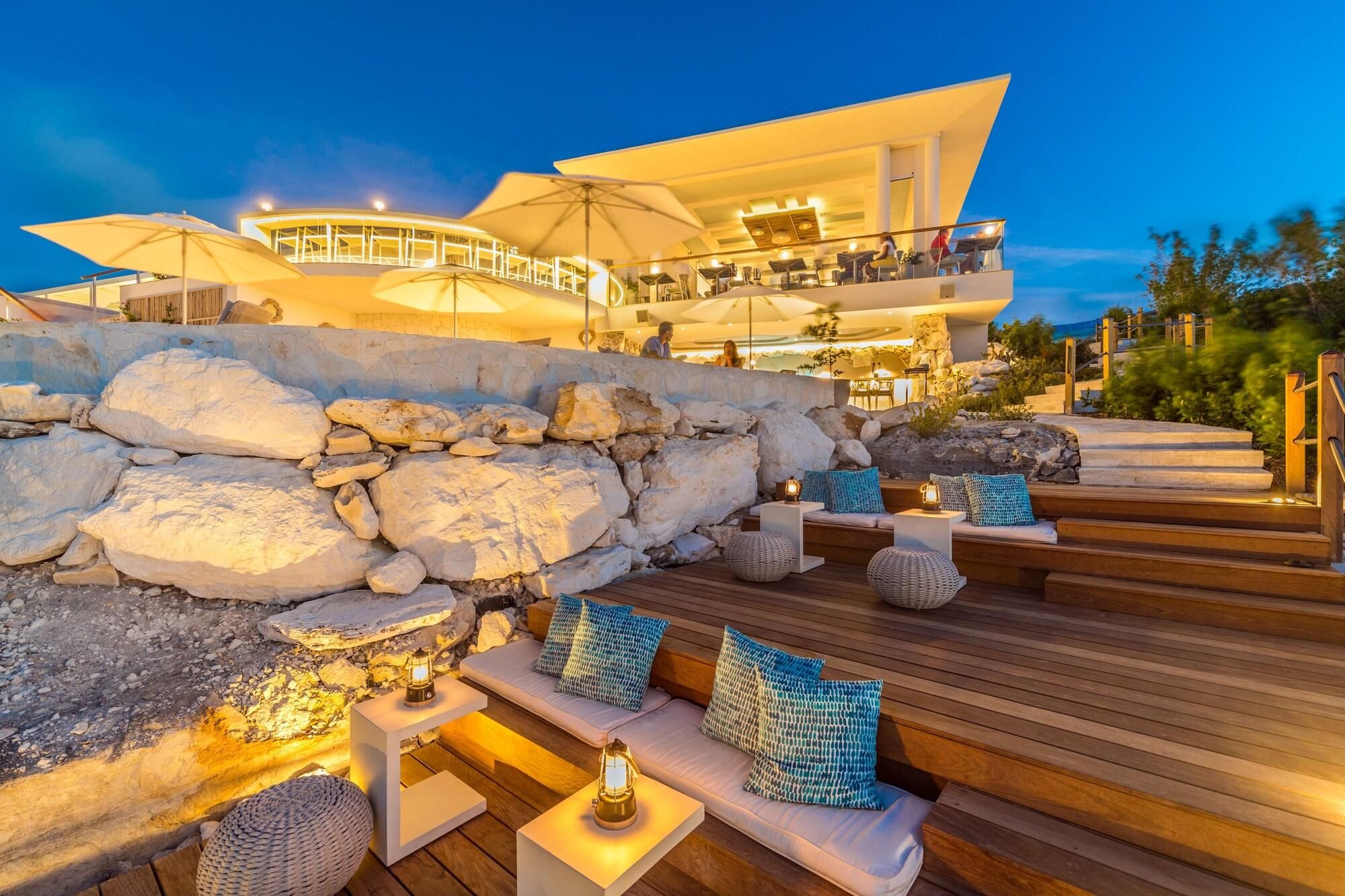 A modern hotel with outdoor seating, a stone wall, and a pool area.