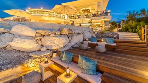 A modern hotel with outdoor seating, a stone wall, and a pool area. - Rock House (Providenciales)