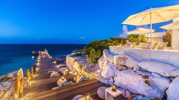 Una terraza de madera con mobiliario exterior y vista al mar.