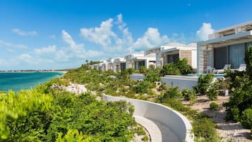 A coastal resort with modern villas, a curved pathway, and a view of the ocean.
