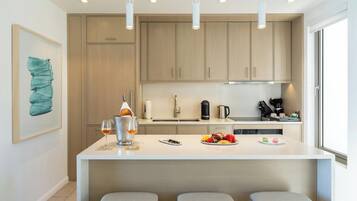 A modern kitchen with a central island, pendant lights, and a large window.