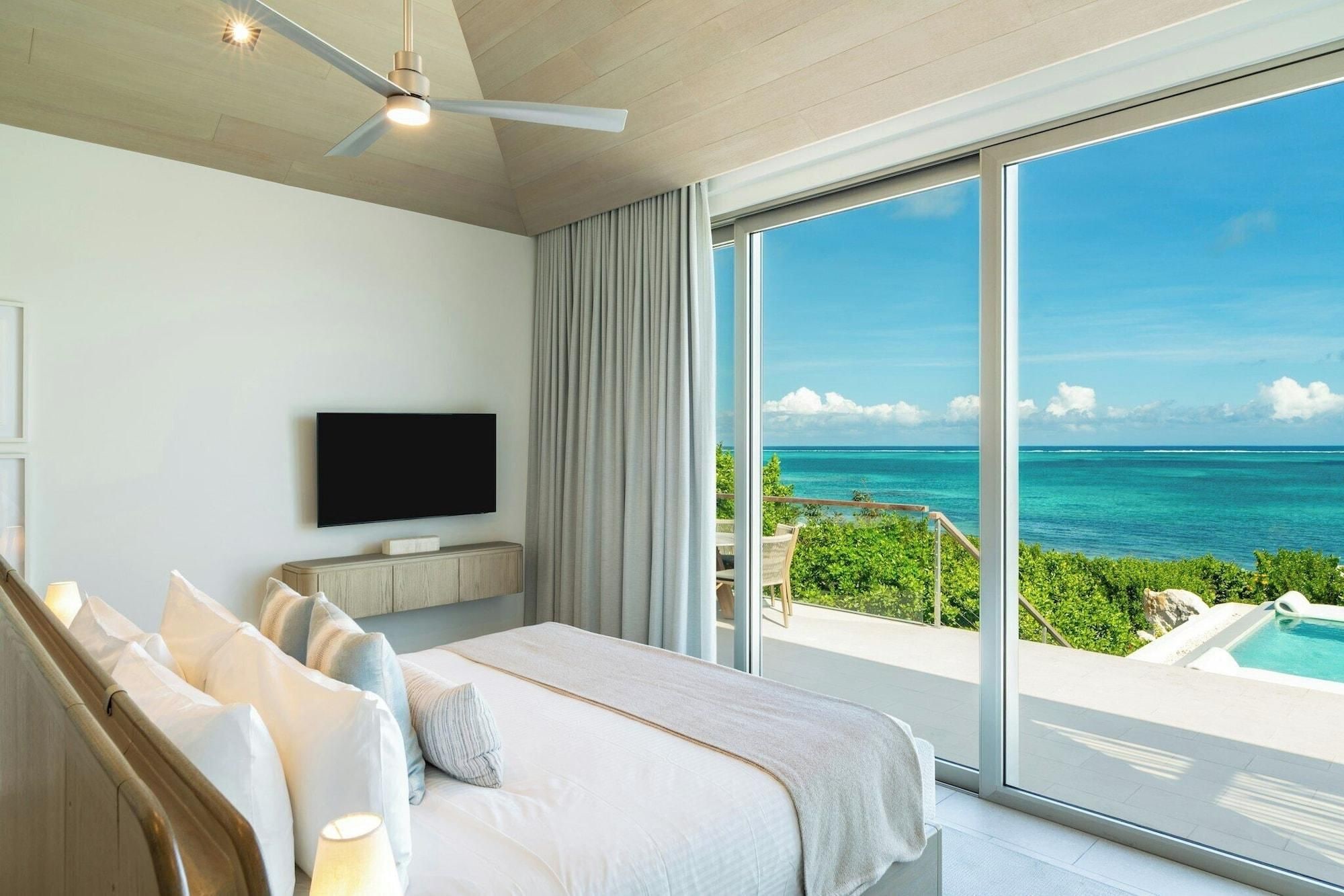 Quarto com cama, televisão e vista para o oceano.