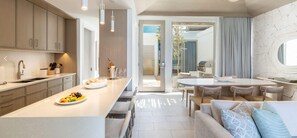 A modern kitchen with a central island, a dining area with a round table, and a living space with a sofa and chairs. - Rock House (Providenciales)
