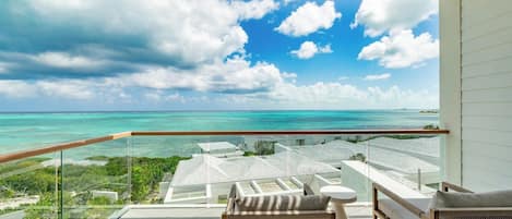 A balcony with a view of the ocean and a resort area.
