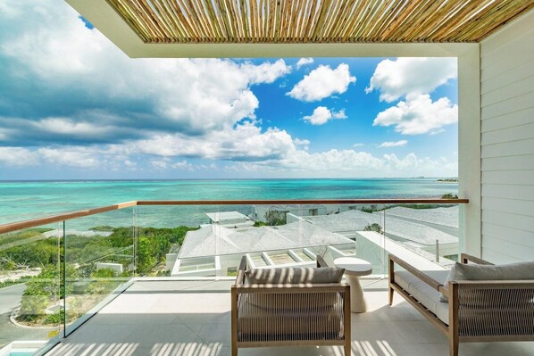 A balcony with a view of the ocean and a resort area. - Rock House (Providenciales)