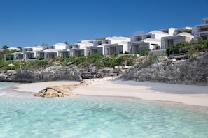 A beachfront hotel with white buildings, clear turquoise water, and rocky terrain. - Rock House (Providenciales)