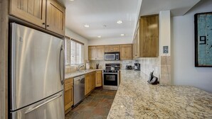 Una cocina moderna con electrodomésticos de acero inoxidable, armarios de madera y encimera de granito.