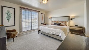 Un dormitorio con una cama grande, un escritorio, una silla y una ventana con persianas.