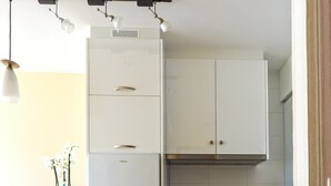 Une cuisine compacte avec des meubles blancs, un four encastré et un réfrigérateur.
