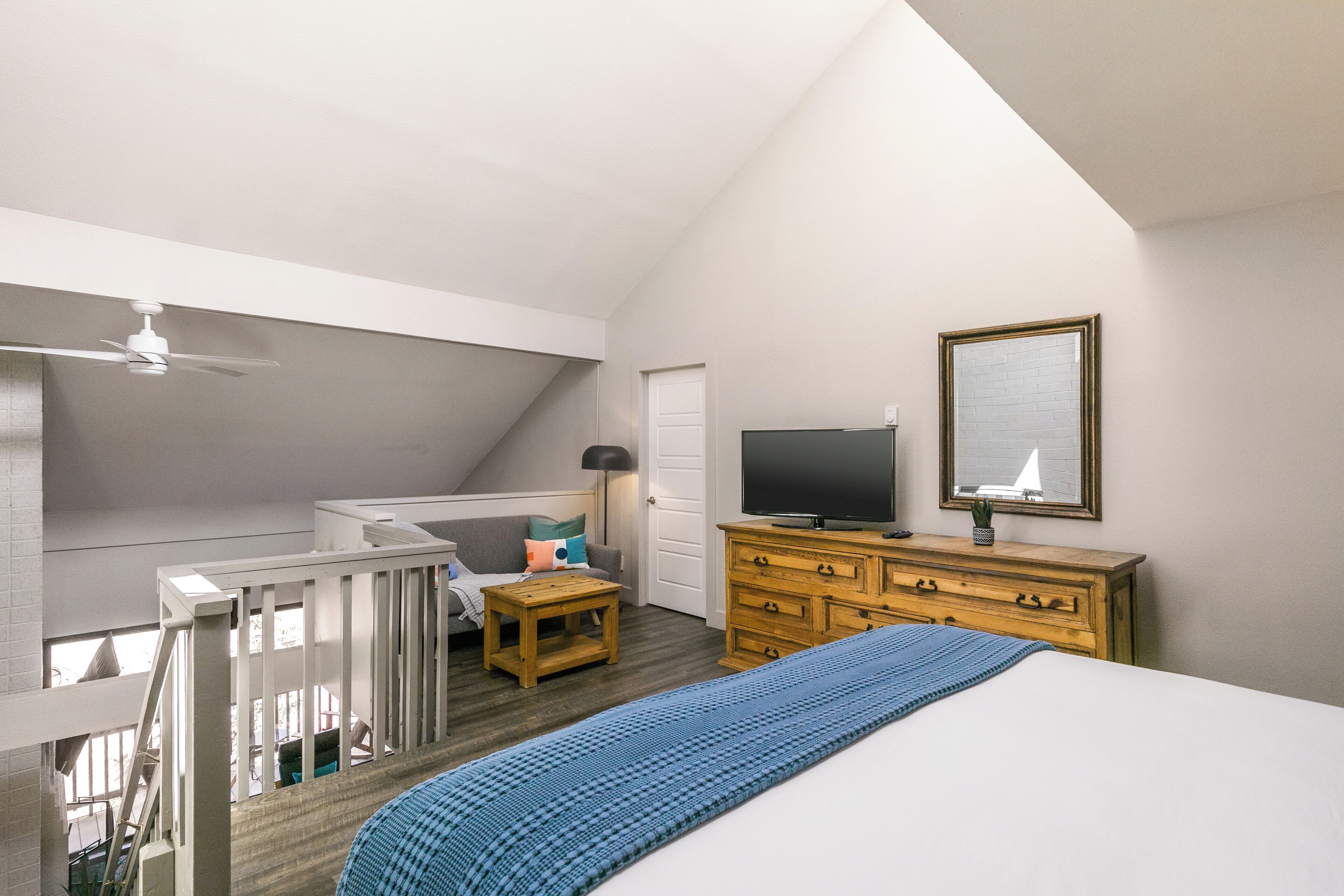 A bedroom with a bed, a TV, a dresser, and a window.