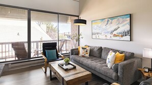 A modern living room with a grey sofa, a wooden coffee table, and a large window offering a view of the outdoors. - Silvertown by AvantStay | Gorgeous Home in Fantastic Location in Park City! (Park City)
