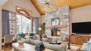 A cozy living room with a stone fireplace, comfortable seating, and a flat-screen TV.