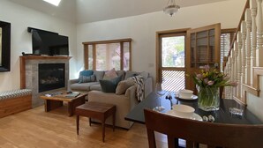 A spacious living room with a fireplace, a sofa, a dining table, and a staircase.