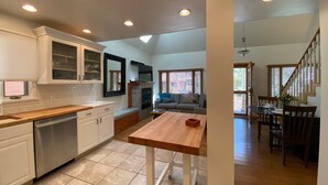A modern kitchen with white cabinets, a wooden countertop, and a built-in dishwasher.