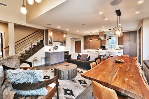 A spacious living area with a large wooden dining table, leather sofas, and a rustic rug.