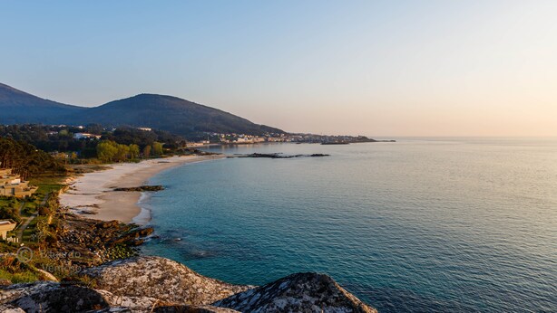 A coastal landscape with a beach, rocky shoreline, and a mountain in the background. - Noia Compostella Wifi (Noia)