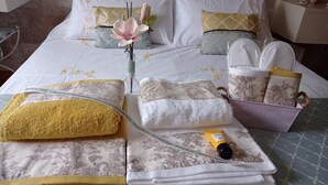 A neatly made bed with floral bedding, a vase with flowers, and a tray with toiletries. - Noia Compostella Wifi (Noia)