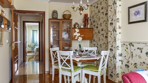 A dining area with a wooden table, white chairs, and a floral wallpaper. - Noia Compostella Wifi (Noia)