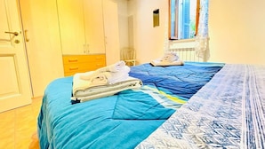A bedroom with a bed, a wardrobe, a chair, and a window with a view. - GuestHost - Cozy 65 sqm apartment, able to accommodate 4 people, located on the 1st floor of a typical medieval building (NO lift). The property is located a short distance from the historic center of Perugia, in the characteristic Sant’Angelo district (Perugia)
