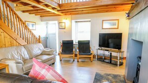 Een woonkamer met een bank, twee stoelen, een televisie en een open haard.