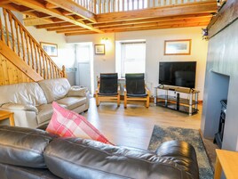 Una sala de estar con un sofá, dos sillones, un televisor y una chimenea.