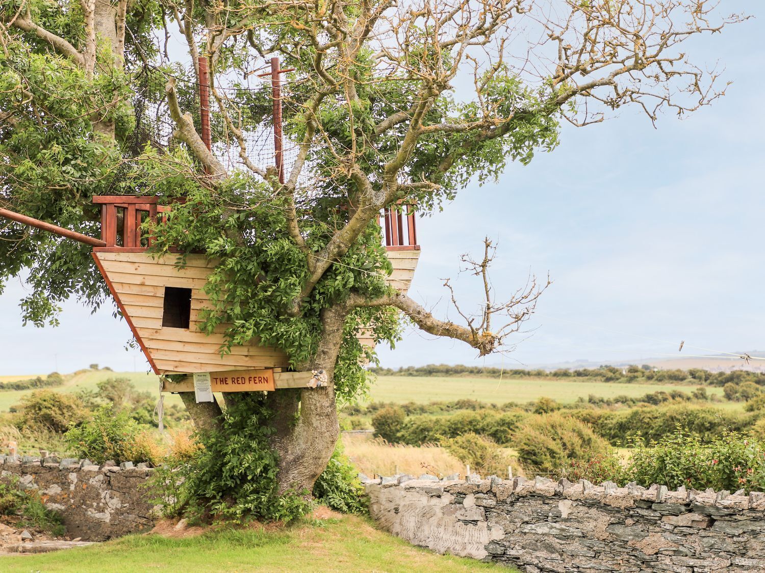 A treehouse with a wooden structure and a sign reading 'The Red Fern.'