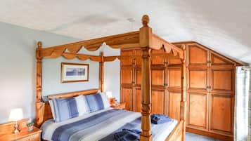 A four-poster bed with a headboard, a bedside table with a lamp, and a nightstand.