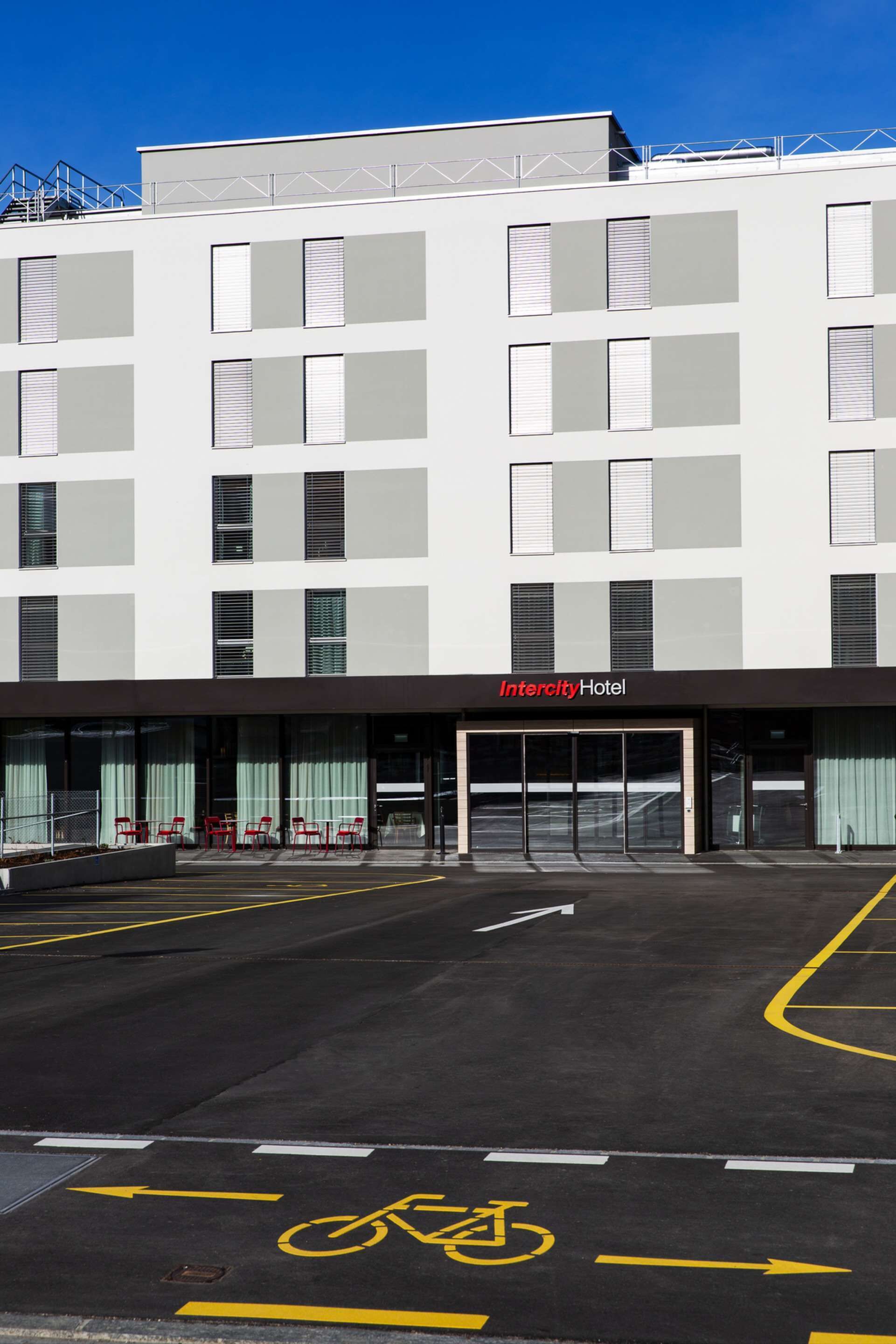 Un moderno Hotel Intercity con fachada plana, amplias ventanas y un estacionamiento con carriles exclusivos para bicicletas.