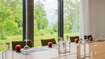 Ein Konferenztisch mit Stühlen, einer Flasche, einem Glas und einem Apfel.
