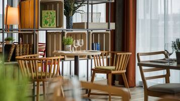 Un comedor con sillas de madera, una mesa redonda y una estantería con libros y objetos decorativos.