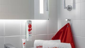 Ein Badezimmer mit einem weißen Waschbecken, einem Spiegel und Toilettenartikeln.