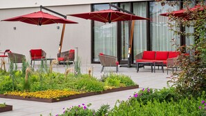 Een terras met rode parasols, rode banken en stoelen.