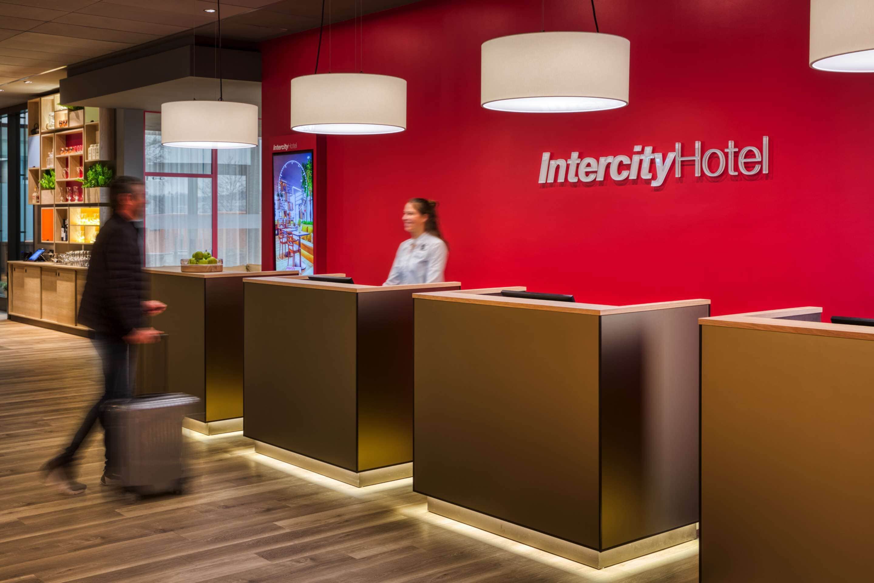 A reception area with a red wall, a reception desk, and a digital screen displaying a map.