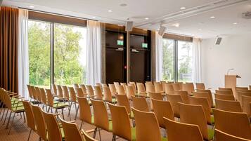 Ein Konferenzraum mit Reihen von Stühlen, großen Fenstern und einer Ausgangstür.
