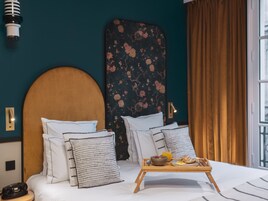 Camera d'albergo con un letto, cuscini, un vassoio con prodotti per la colazione, un telefono e un punto luce a parete.