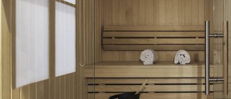 A sauna with wooden benches, a black bucket with a wooden handle, and two clocks on the wall.