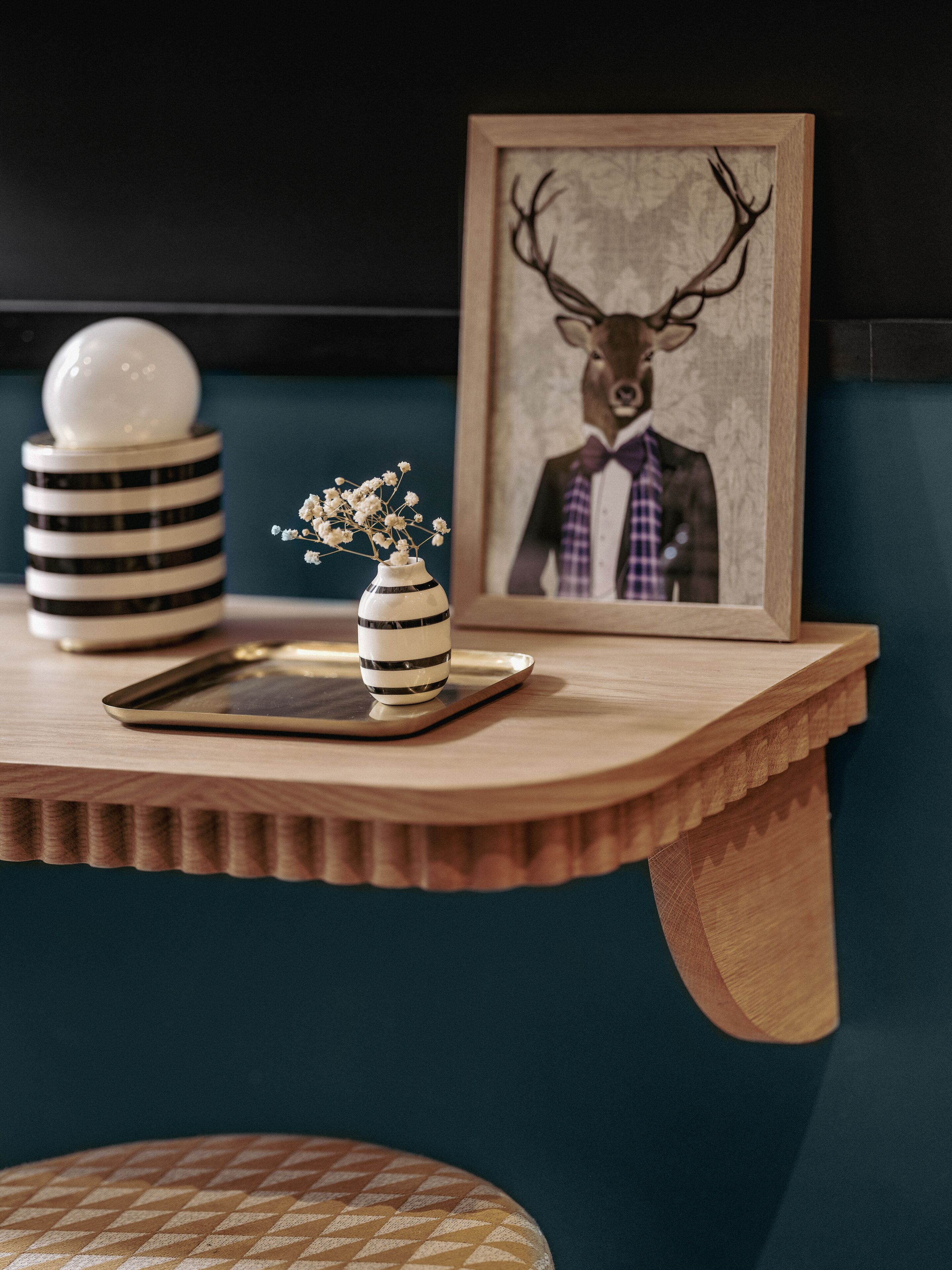 A wooden table with a vase of flowers, a framed picture, and a spherical object.