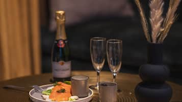 Ein Tisch mit Essen, einer Champagnerflasche, zwei Gläsern und einer Vase mit Dekoration.