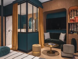 Una sala de estar moderna con un sofá, un sillón, un otoman, una mesa de centro y una estantería.