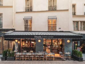 A hotel named Dandy Hotel & Kitchen with outdoor seating and a striped awning. - Dandy Hotel  (Paris)