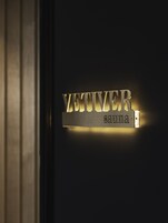 A metallic sign with the name "VETIVER" and the word "Sana" on a dark background.