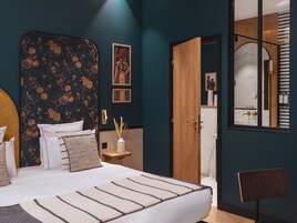 A bedroom with a bed, a nightstand, a mirror, and a door leading to a bathroom.