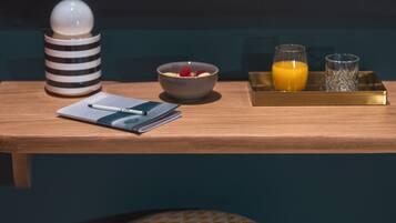 A wooden table with a notebook, pen, bowl of cereal, and a tray with a glass of orange juice and a glass of water.