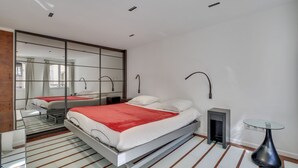 Un dormitorio moderno con una cama grande, una mesa de vidrio y un espejo.