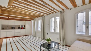 Una habitación moderna con cocina, ventanas amplias y una cama.