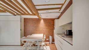 Una cocina moderna con armarios blancos, techo de madera y pared de ladrillo.